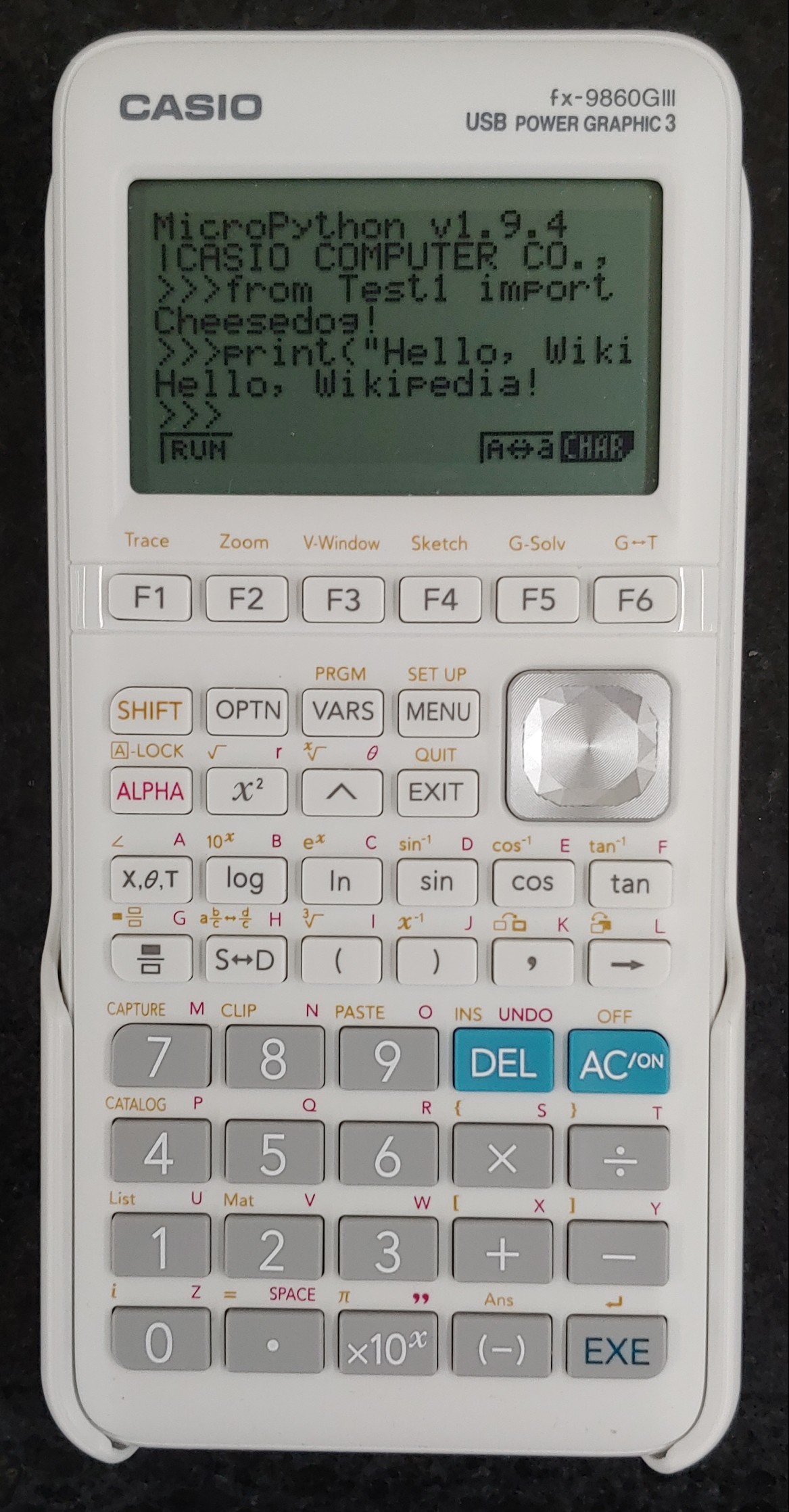 Máy tính đồ thị Casio fx-9860GIII đang chạy MicroPython với lệnh in ra màn hình Hello Wikipedia