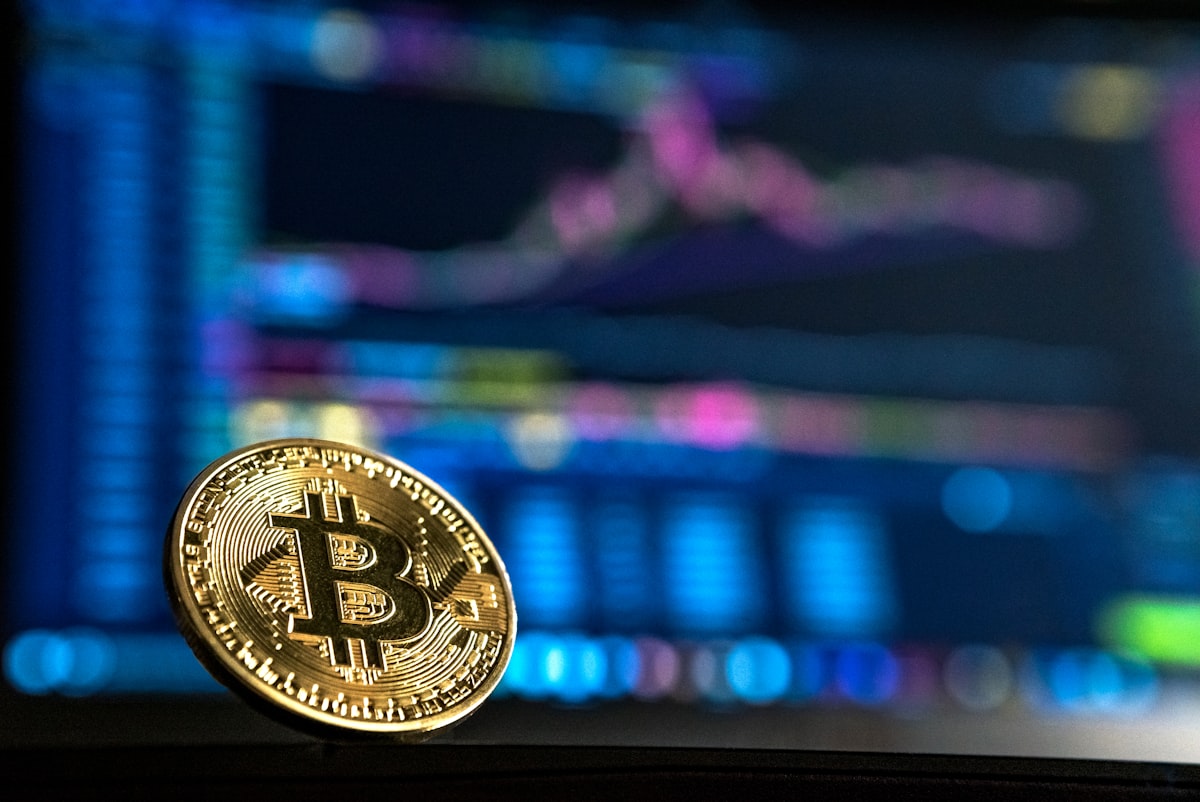 Đồng Bitcoin vàng đặt trên nền biểu đồ nến mờ thể hiện thị trường tiền mã hóa