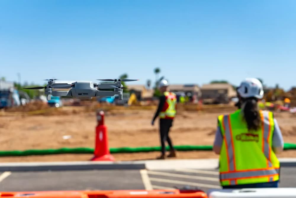 Drone bay ghi hình công trường xây dựng với công nhân mặc áo phản quang bên dưới