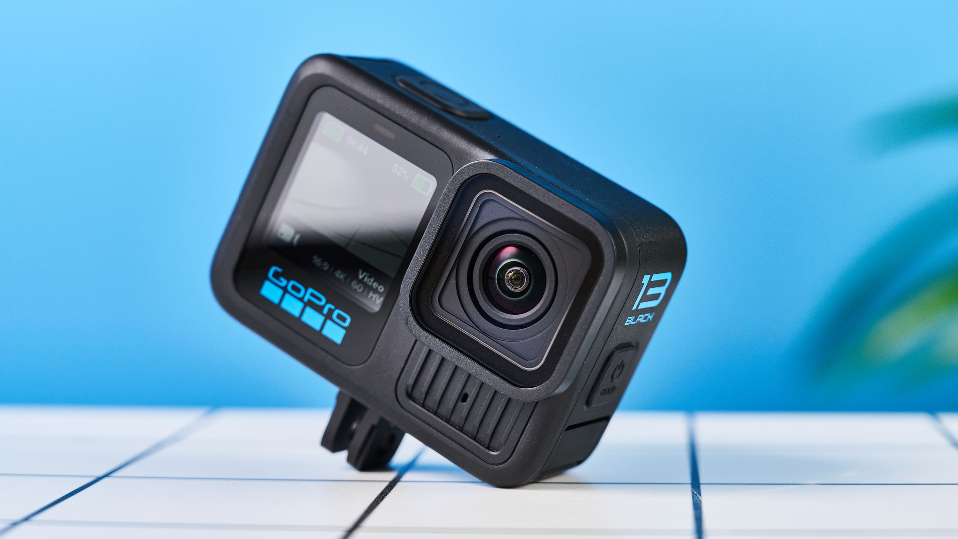 GoPro Hero 13 Black đặt trên sàn gạch trắng nền xanh dương với màn hình hiển thị thông số quay phim