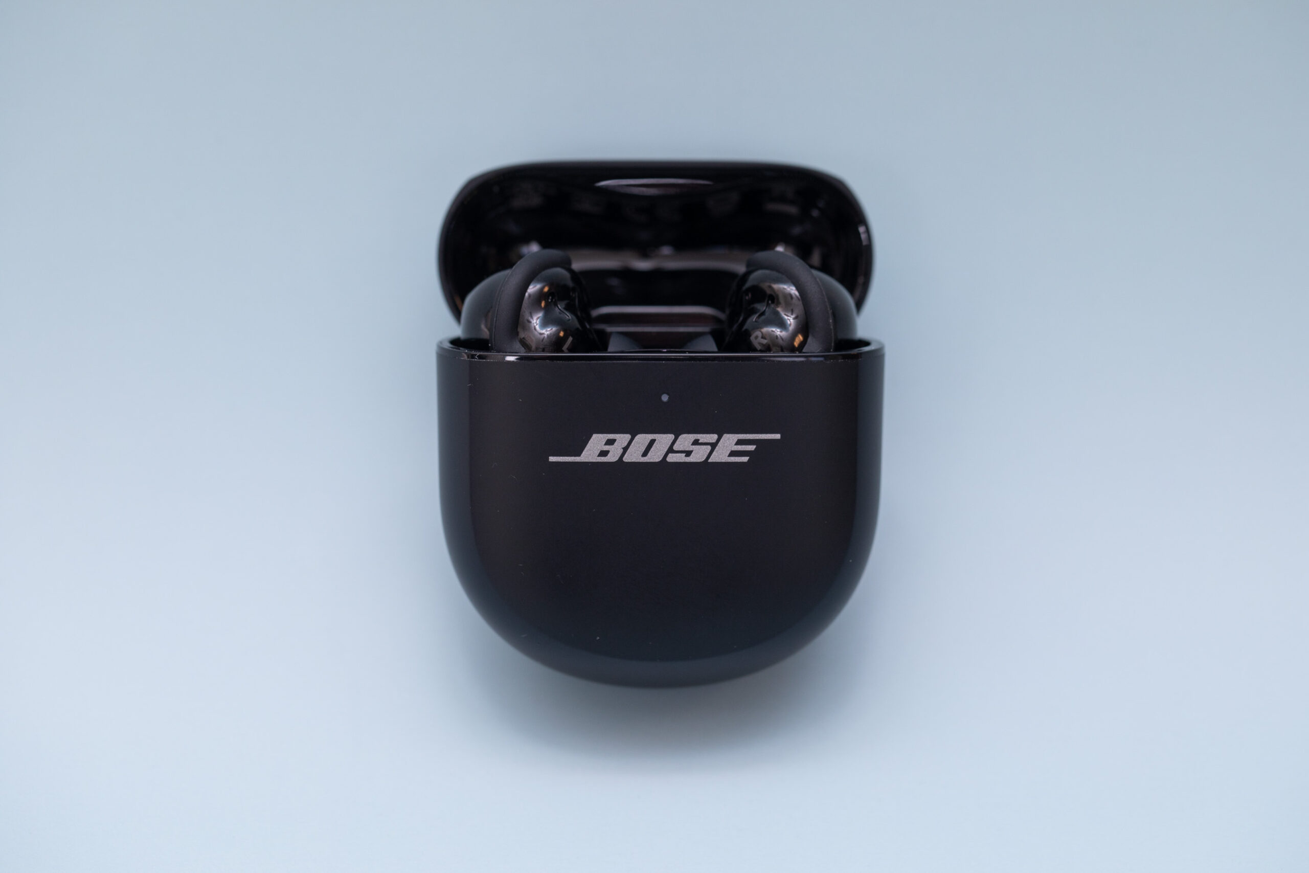 Bose QuietComfort Ultra Earbuds nằm trong hộp sạc màu đen mở trên nền xám