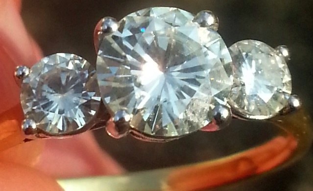 Nhẫn cưới moissanite cắt tròn đeo trên ngón tay cưới dưới ánh sáng tự nhiên