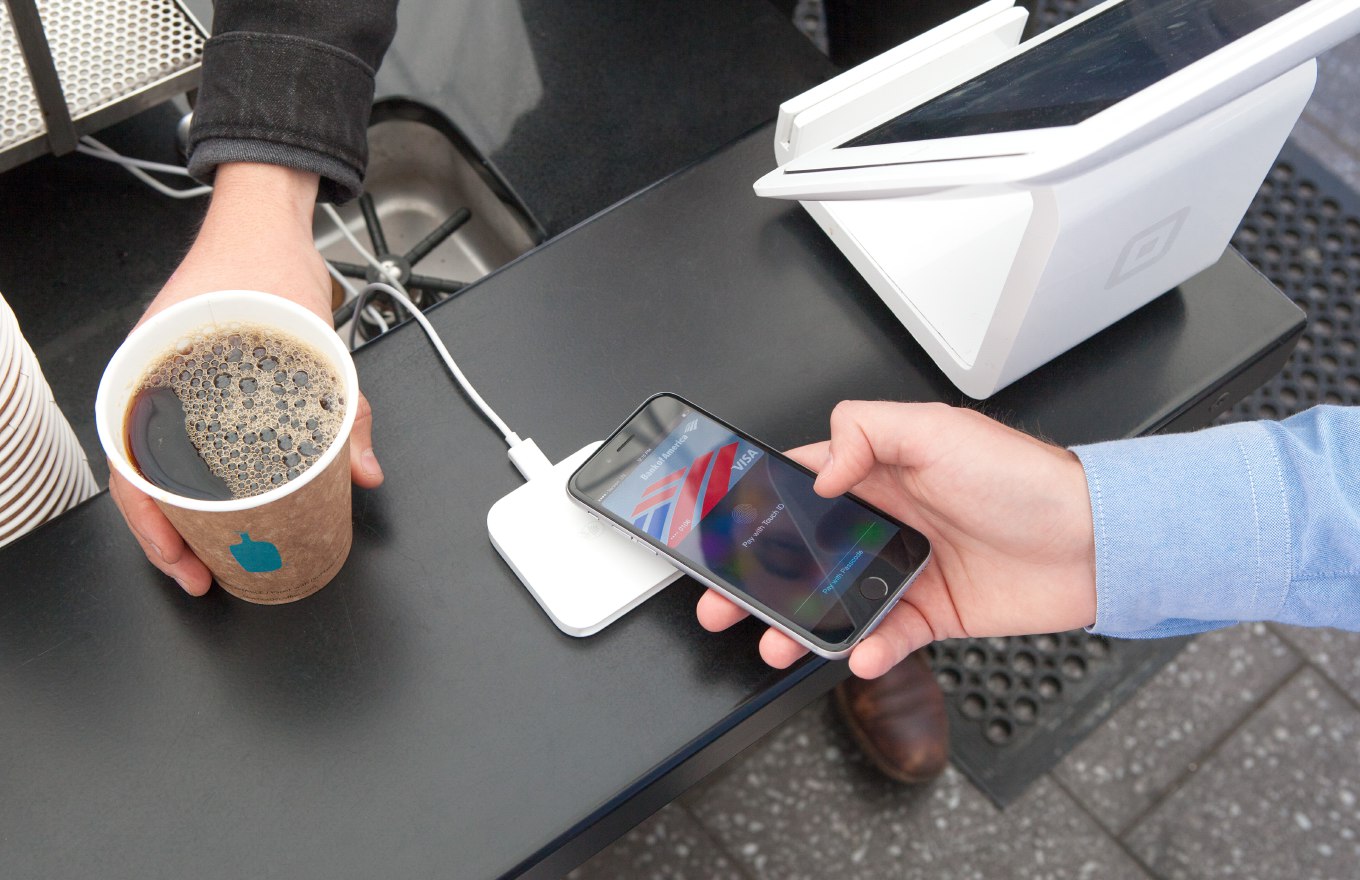 Điện thoại iPhone chạm máy POS thanh toán không tiếp xúc Apple Pay tại quầy cà phê