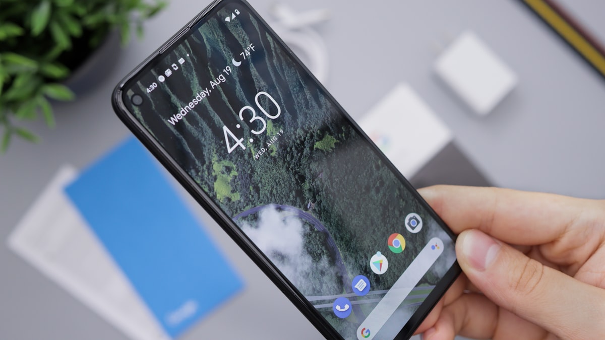 Bàn tay cầm điện thoại Android hiển thị màn hình khóa với widget đồng hồ và thời tiết