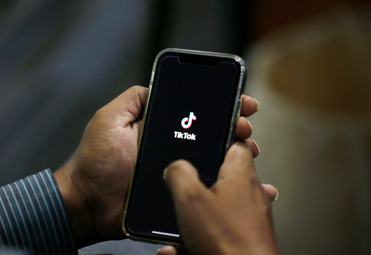 Người dùng mở ứng dụng TikTok trên điện thoại, màn hình hiển thị giao diện video ngắn