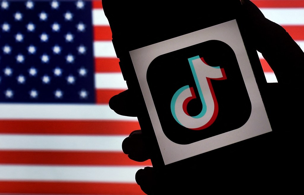 Điện thoại hiển thị logo TikTok trước nền cờ Mỹ, minh họa thương vụ chuyển nhượng
